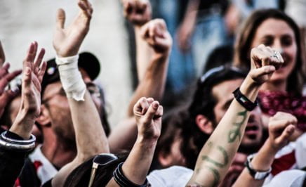 A jubilant multinational crowd, with hands in the air, cheering