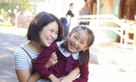 Older woman laughs with child in school uniform