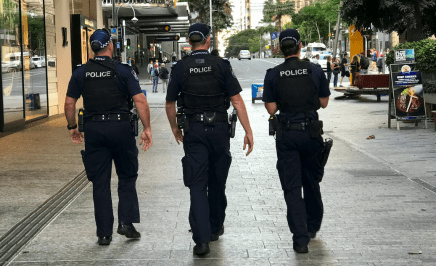 Three uniformed police officers walk the street in QLD.