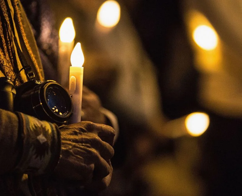 An activist holds a camera and a candle at a vigil