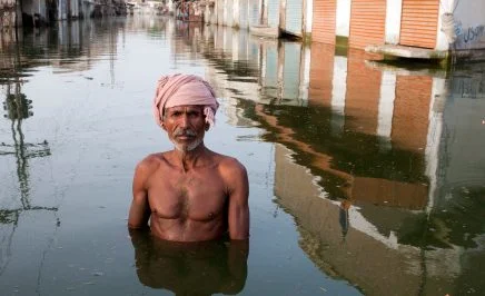 A man stands chest-deep in flood waters in Pakistan