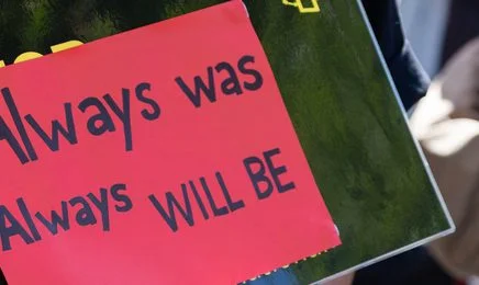 Closeup of placard displaying the handwritten message 