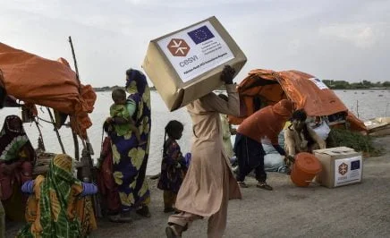 A man carries relief items along the only surviving road in the area. Numerous roads and bridges have been washed away or severely damaged, impeding access to many areas.